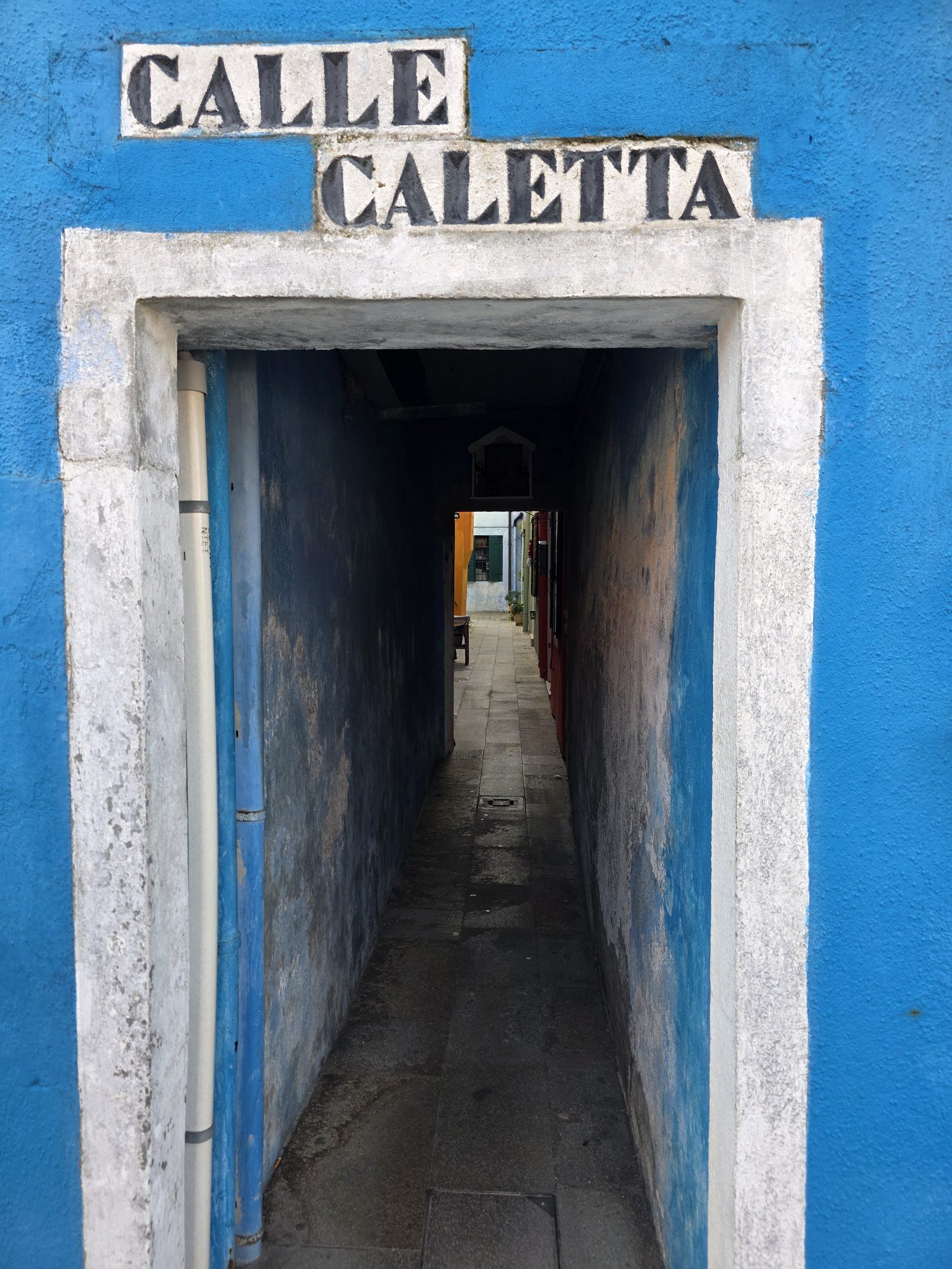 Blau gestrichener Durchgang in einer Gasse von Burano