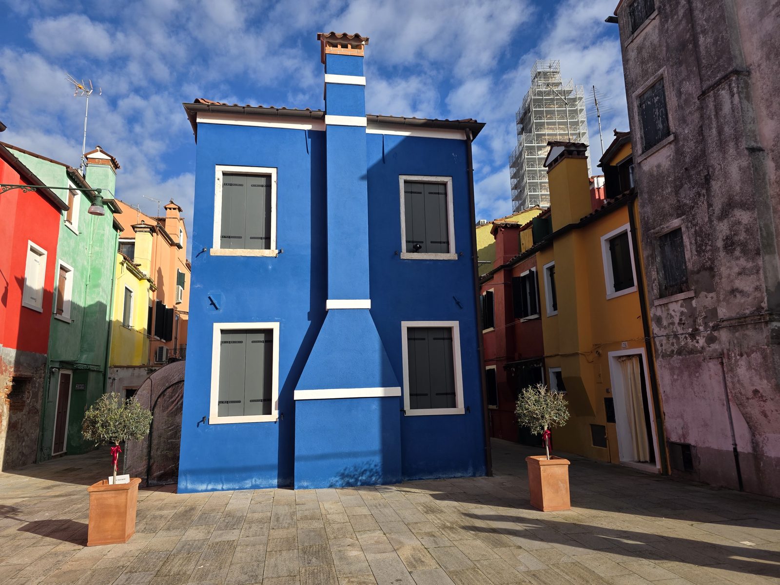 Der schiefe Campanile von San Martino hinter einem blauen Haus in Burano